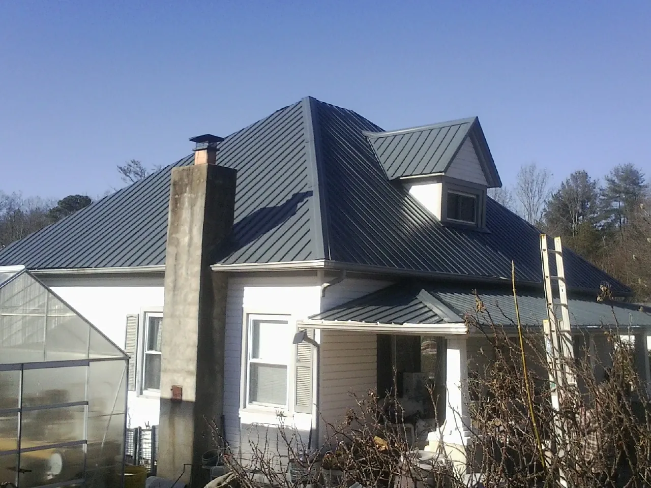 Dark blue standing seam metal roof on a white farmhouse with dormer — Slate & Tile Roof Repair by Roofing Brothers in Berkeley