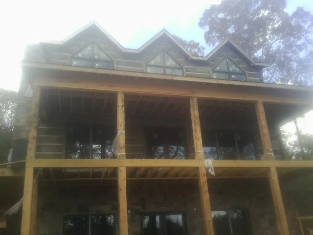 Dormers and porch framing on a large log home under construction — Roof Coating work by our crew in Berkeley
